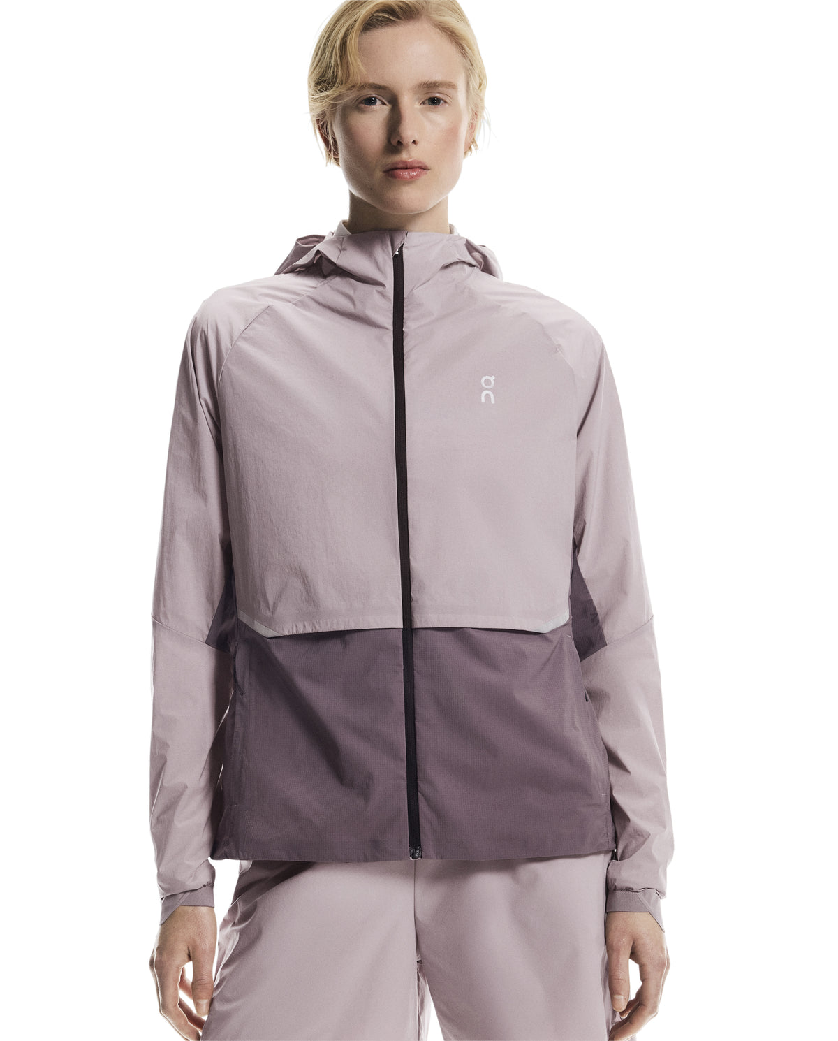 Person wearing a two-tone jacket with a visible brand logo on a white background