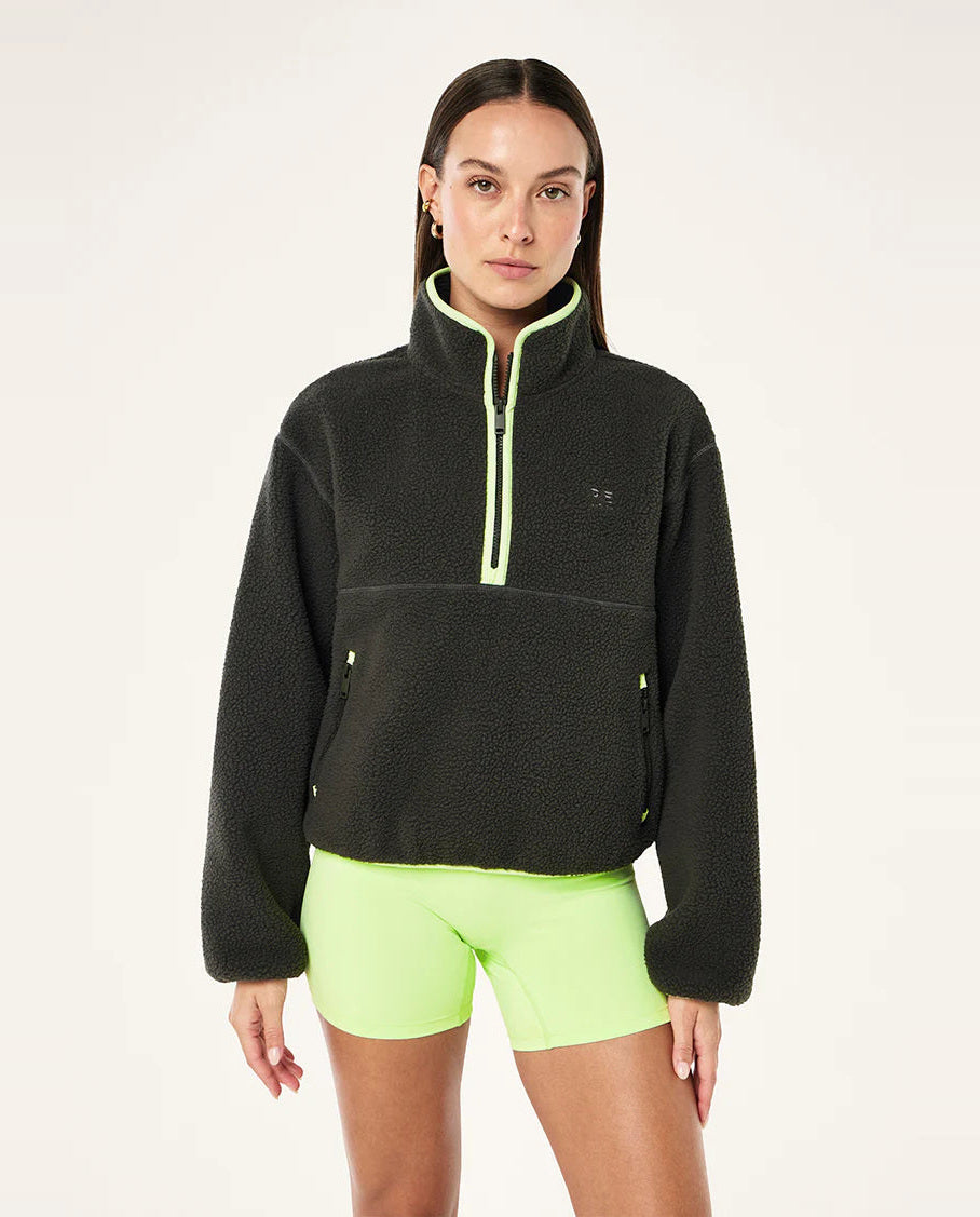 female model wearing  a grey teddy fleece with lime green highlights on a white background