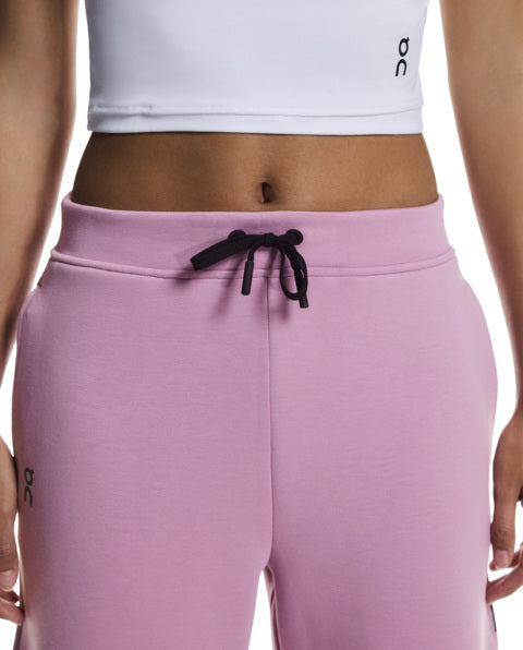 Person wearing a white crop top and pink sweatpants with a brand logo on a white background
