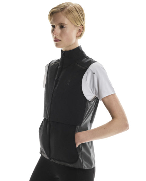 Woman wearing a black and gray vest gilet over a white shirt on a white background