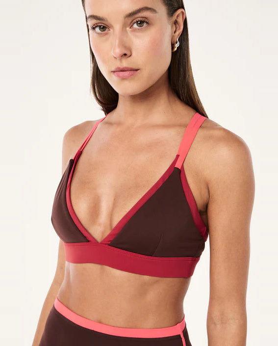 Woman wearing a brown and pink sports bra on a white background