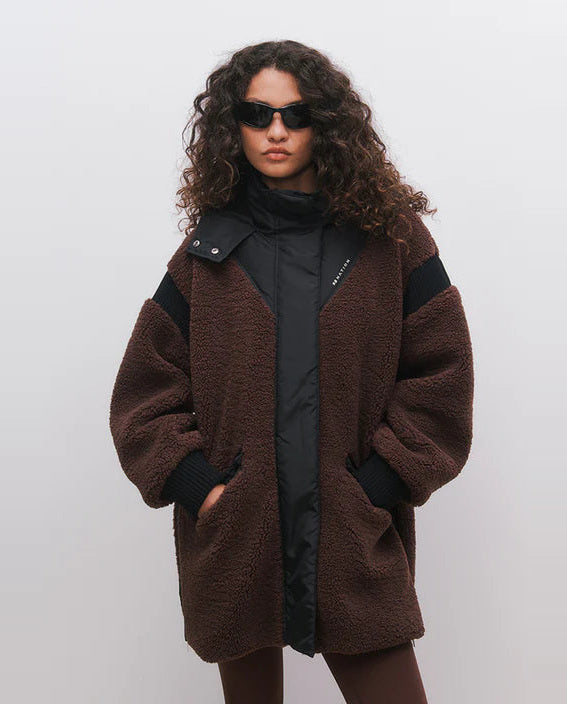 Woman wearing a brown coat with black accents on a white background