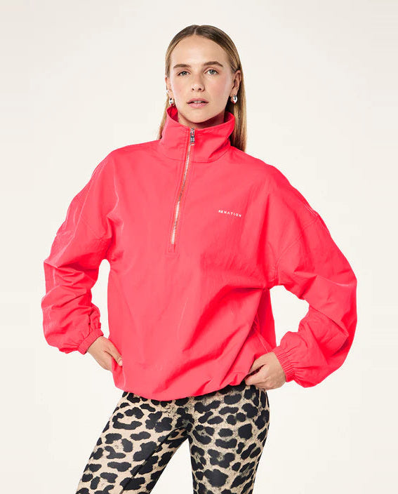 Woman wearing a bright pink jacket with a brand logo on a white background
