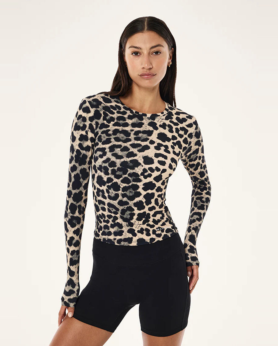 Woman wearing a leopard print long-sleeve top and black bike shorts on a white background