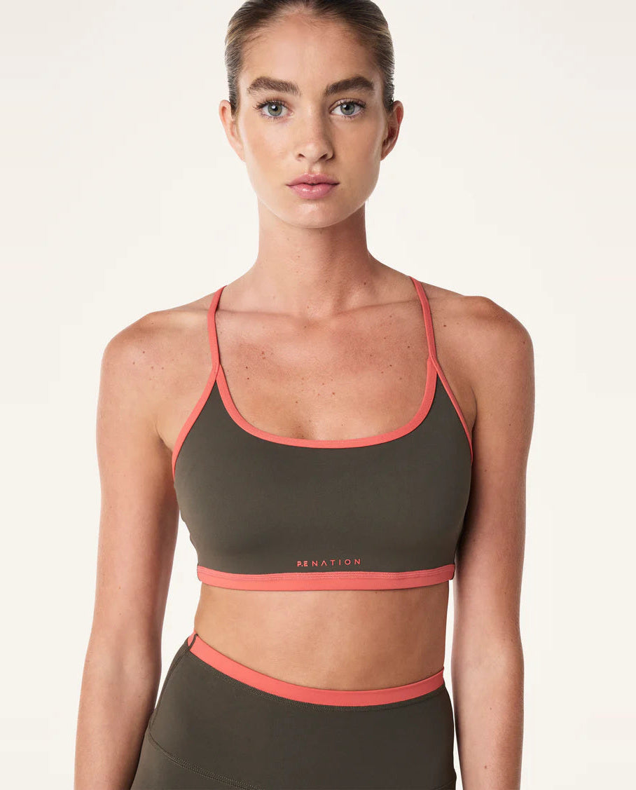 person wearing a Women's P.E Nation Fundamental Tarmac/Brick Red Sports Bra with a white background 