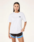 Woman wearing a white t-shirt with a logo and black shorts with blue accents on a white background