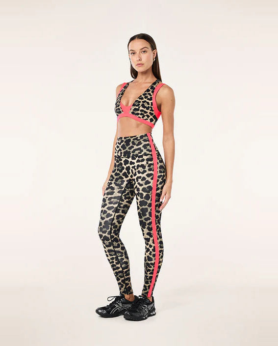 Woman wearing a leopard print sports outfit with pink accents on a white background