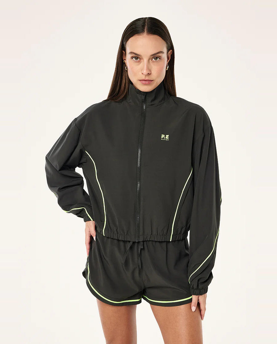 Woman wearing a grey  tracksuit with green highlights a logo on a white background