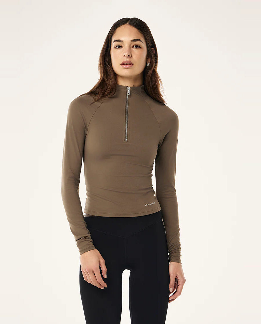 Woman wearing a brown long-sleeve top with a zipper on a white background