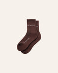 Pair of brown socks with 'PE Nation' branding on a beige background