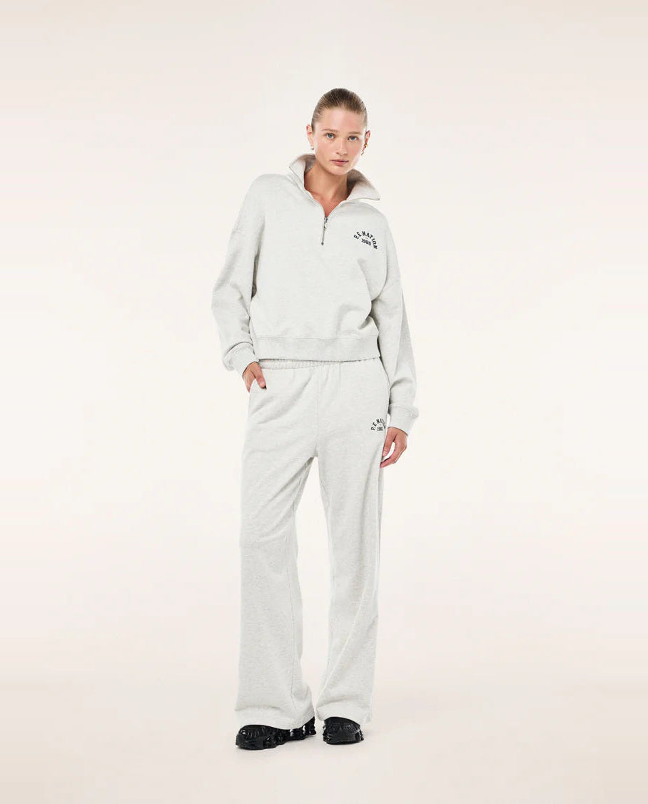 Person wearing a light grey P.E Nation tracksuit with a logo on a white background