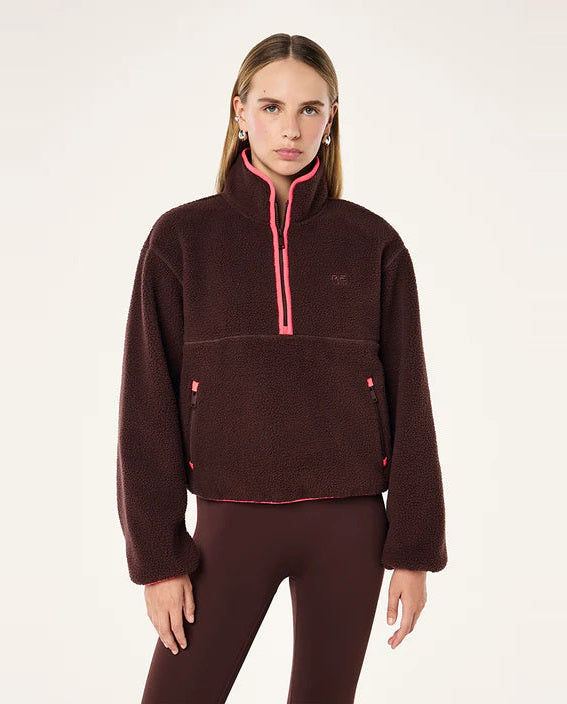 Woman wearing a brown fleece pullover with pink accents on a white background