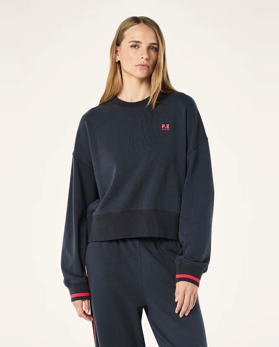 Person wearing a navy blue sweatshirt with a small red logo on a white background