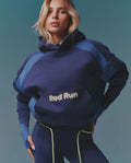 Woman wearing a blue tracksuit with 'Red Run' text on a teal background