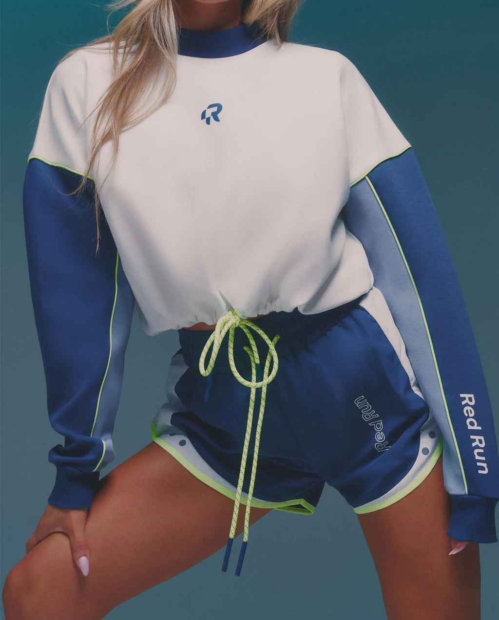 Person wearing a blue and white athletic outfit with a visible brand logo on a teal background