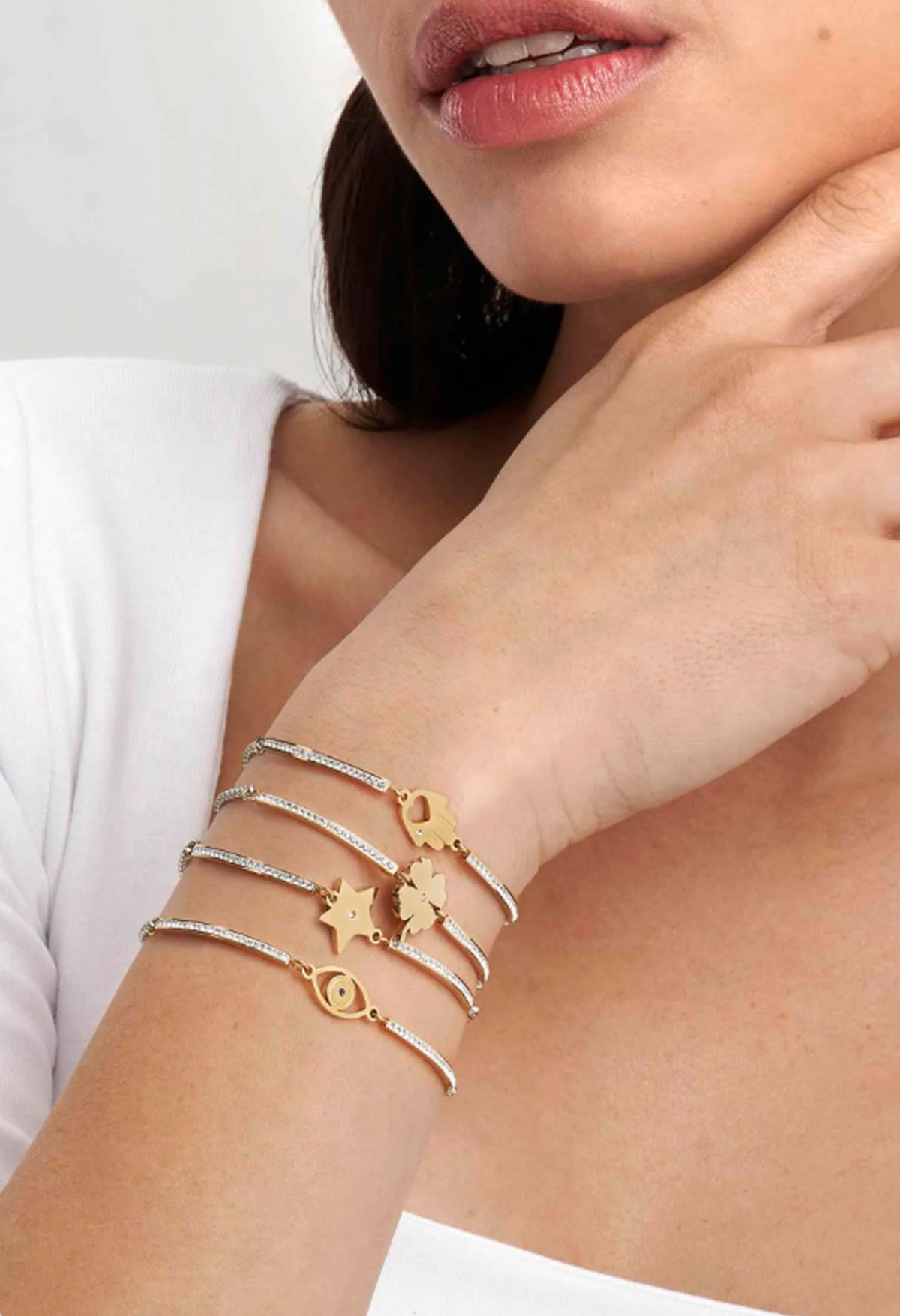 Woman wearing Nomination Milleluci bracelet set, gold and stainless steel charm bracelets on wrist.