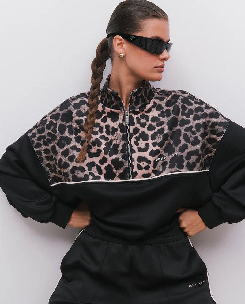 Person wearing a black and leopard print tracksuit against a white background