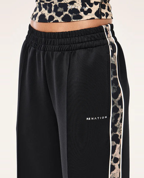 Black track pants with leopard print side strip and cropped top on a white background