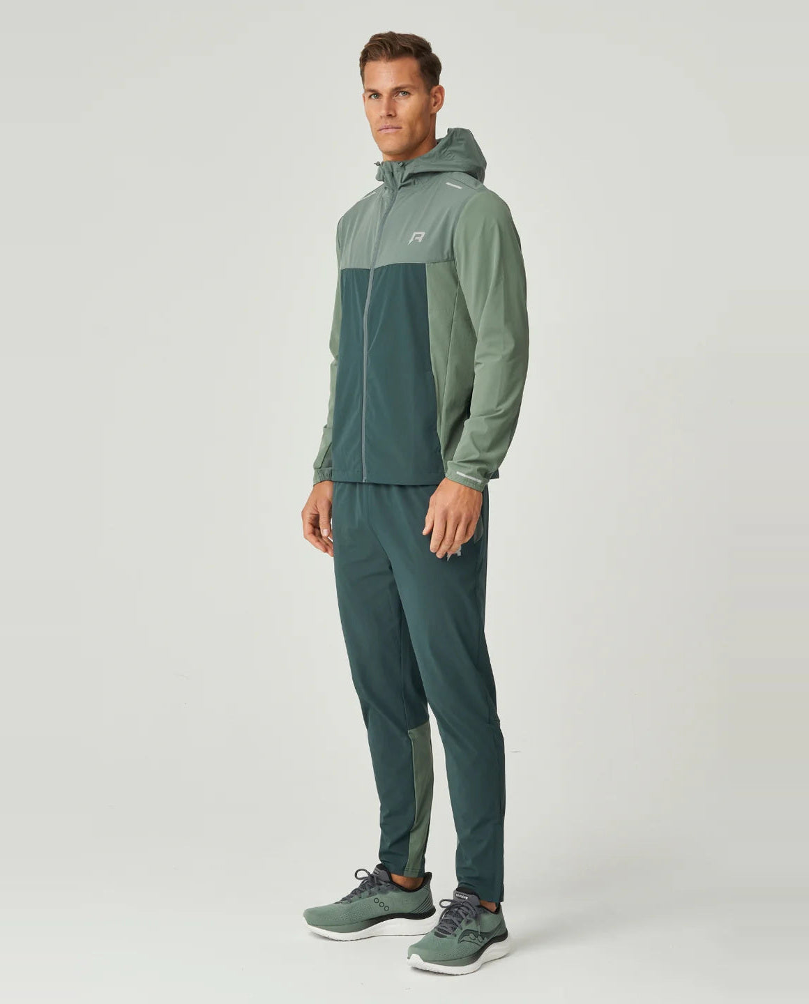 Man wearing a green tracksuit with a hood  with reprimo logo on chest on a white background