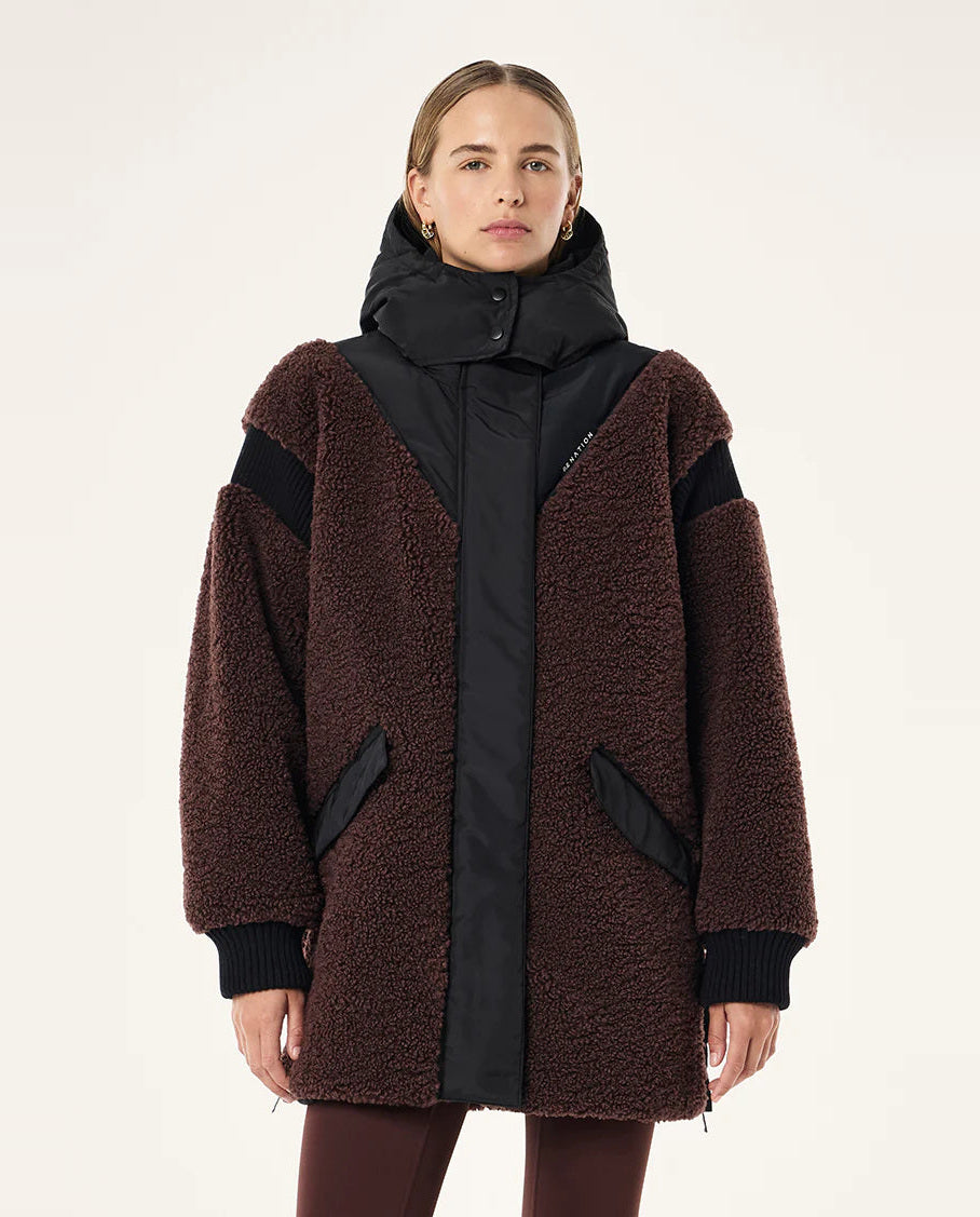 Woman wearing a brown and black coat with a hood on a white background