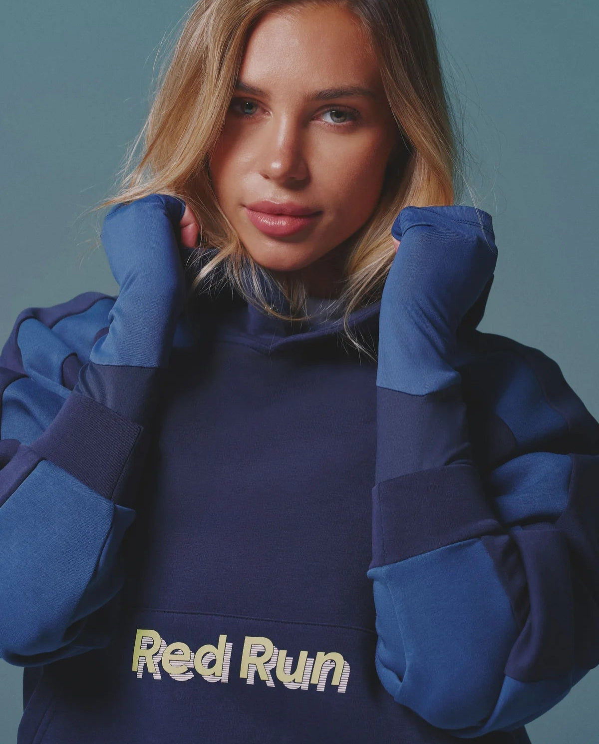 Person wearing a blue hoodie with 'Red Run' text against a teal background