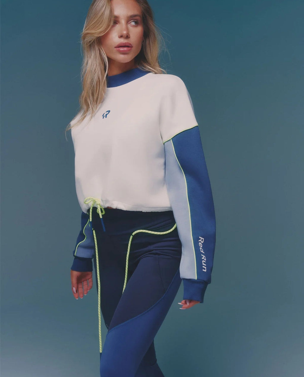 Woman wearing a white and blue outfit with a brand logo on a blue background