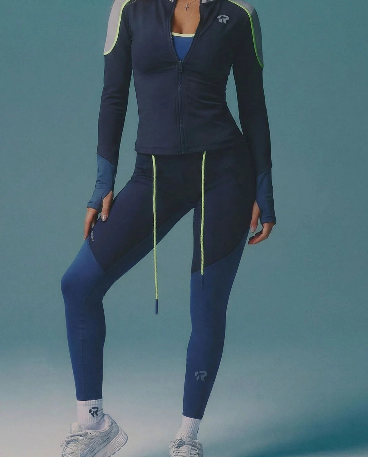 Person wearing a blue athletic outfit with white accents on a teal background