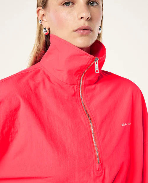 Person wearing a red jacket with a brand logo on a plain background