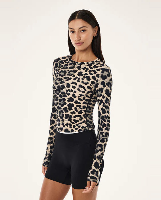 Woman wearing a leopard print long-sleeve top and black shorts on a white background