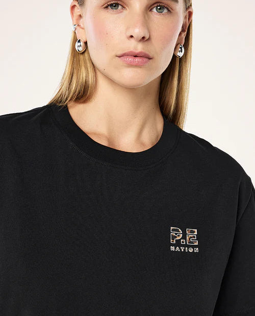 Person wearing a black t-shirt with a logo on a plain background