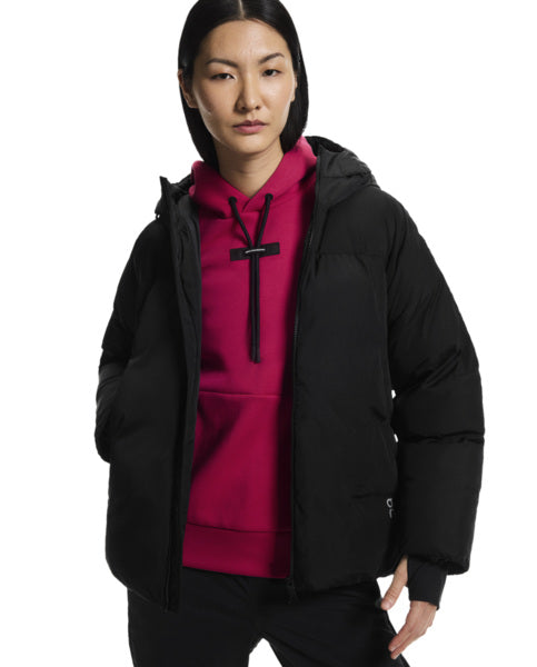 Person wearing a black jacket over a pink hoodie on a white background