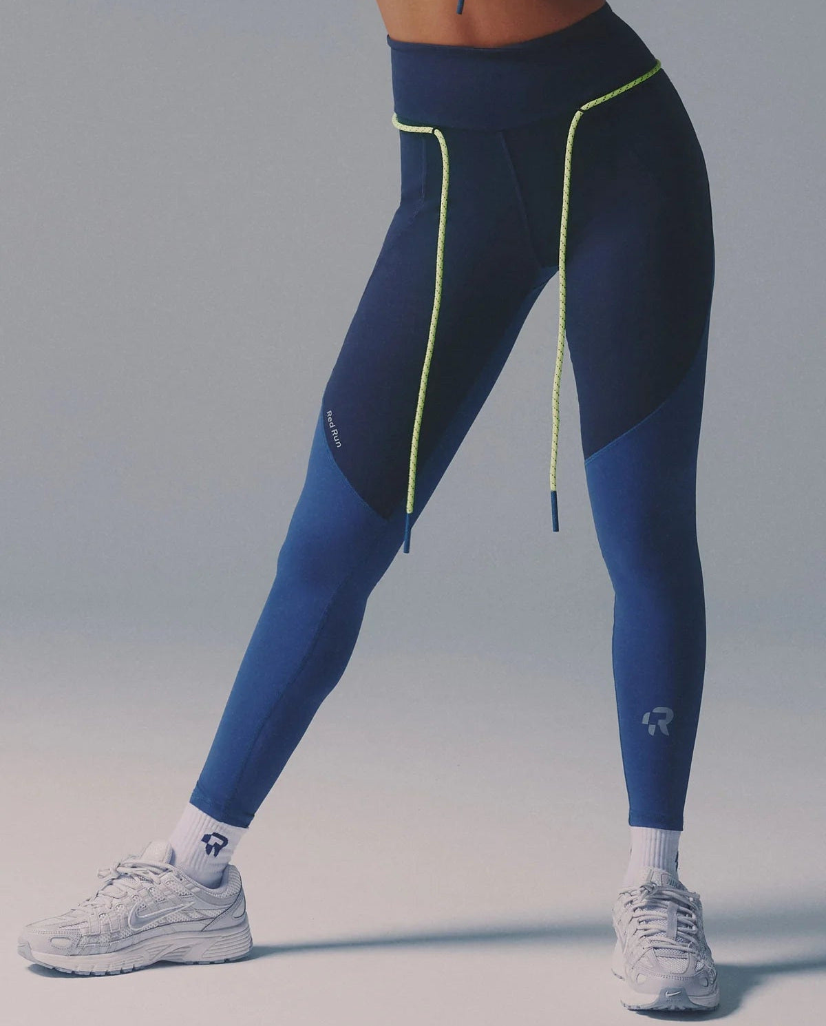 Person wearing blue and black leggings with a gray background