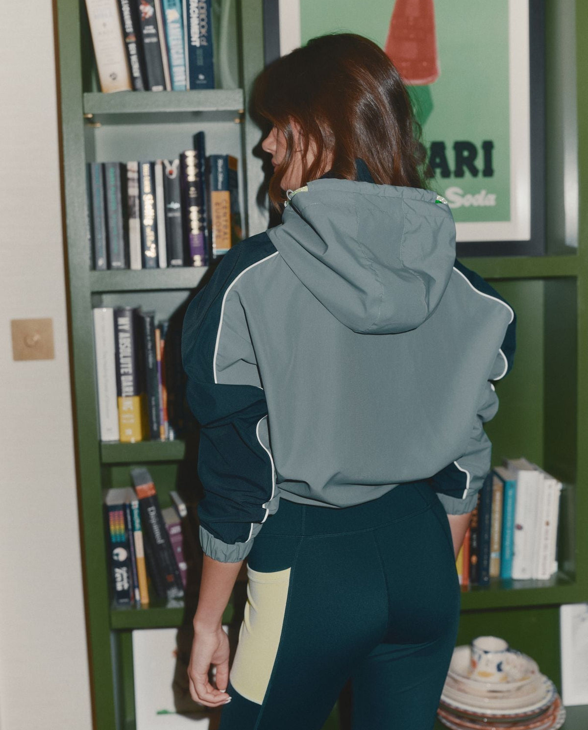 Person wearing a green and white jacket with 'Red Run' branding in front of a bookshelf.