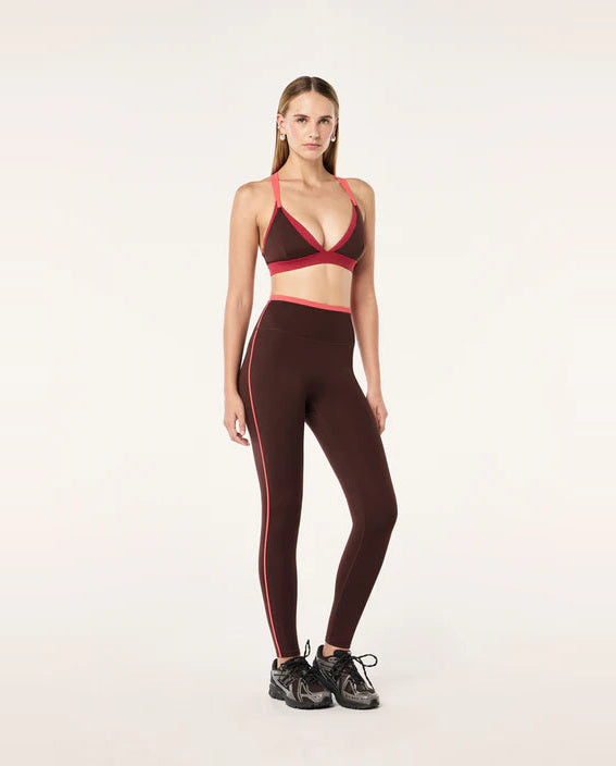 Woman wearing a brown and red sports bra and leggings set on a white background
