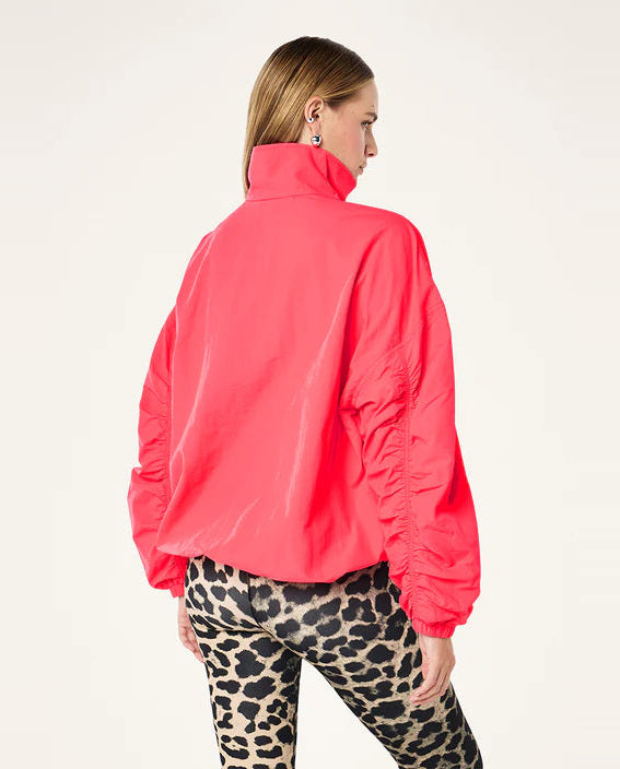 Person wearing a bright pink jacket and leopard print pants on a white background