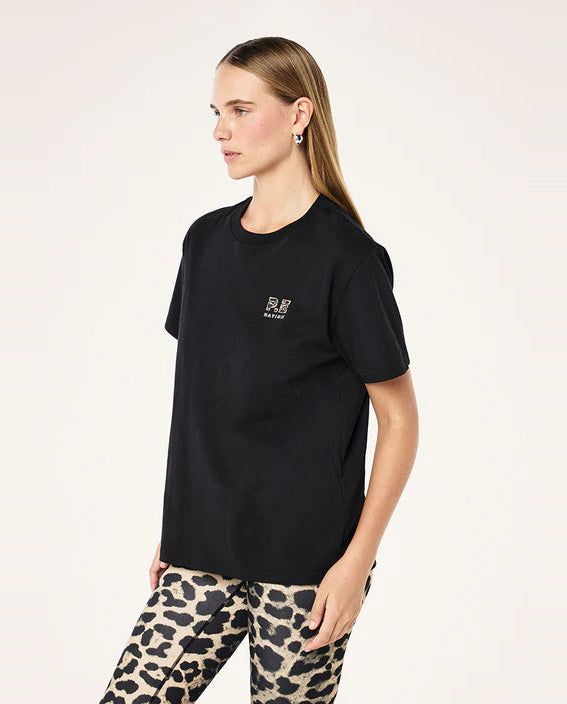 Woman wearing a black t-shirt with a logo and leopard print pants on a white background