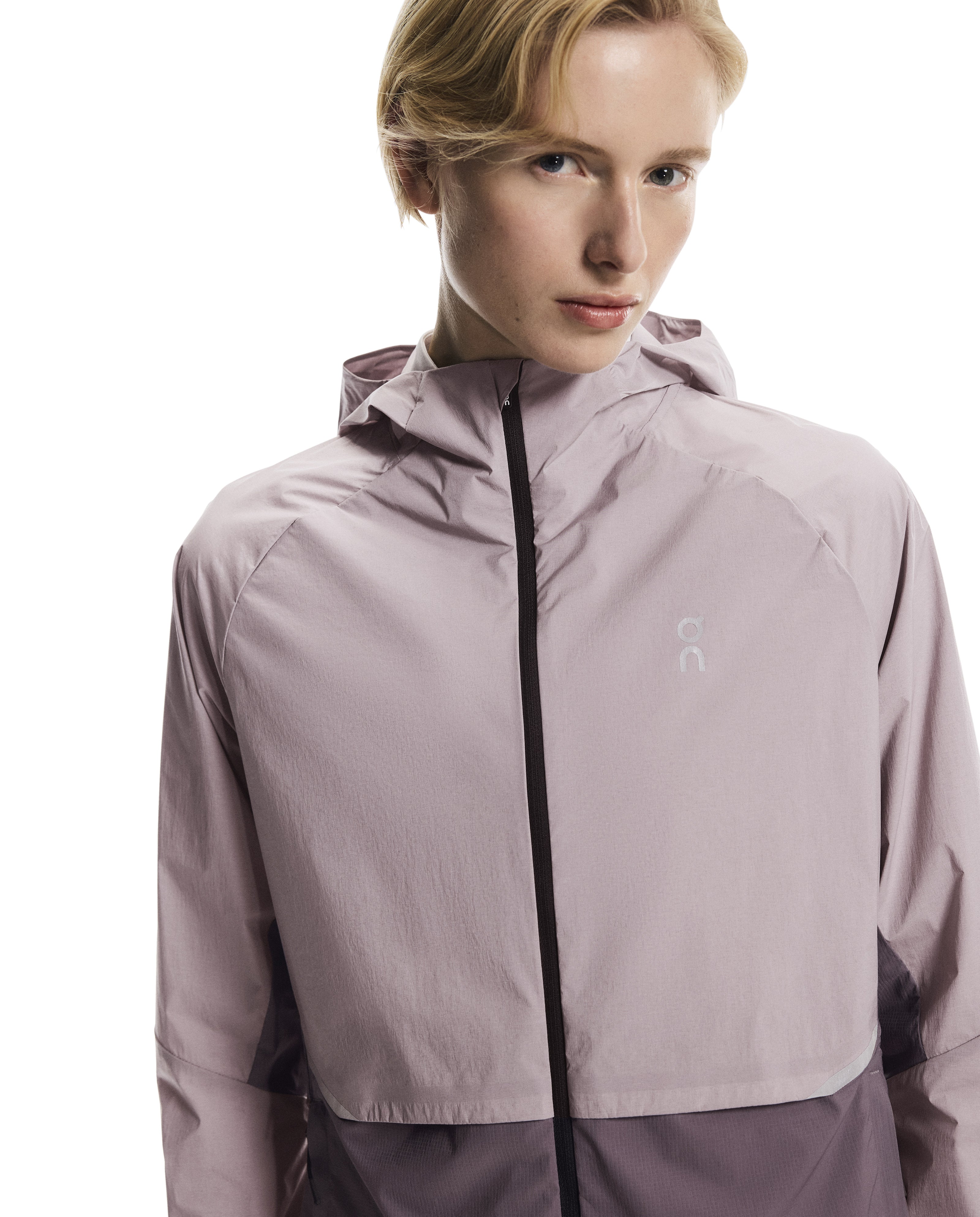 Person wearing a light purple jacket with a brand logo on a white background