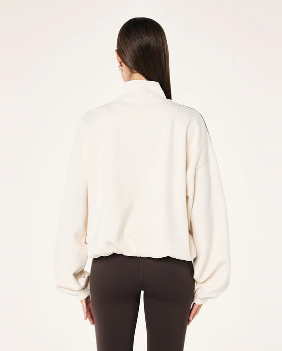 Woman wearing a white athletic jacket with black accents on a white background.
