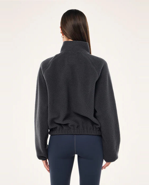 Person wearing a dark blue sweater and dark blue pants on a white background