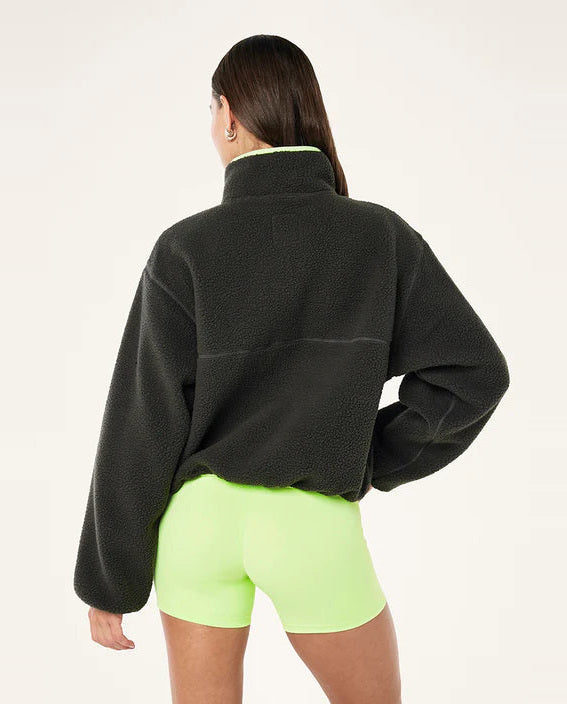 female model wearing  a grey teddy fleece with lime green highlights on a white background