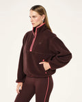 Woman wearing a brown fleece pullover with pink accents on a white background