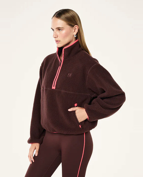 Woman wearing a brown fleece pullover with pink accents on a white background