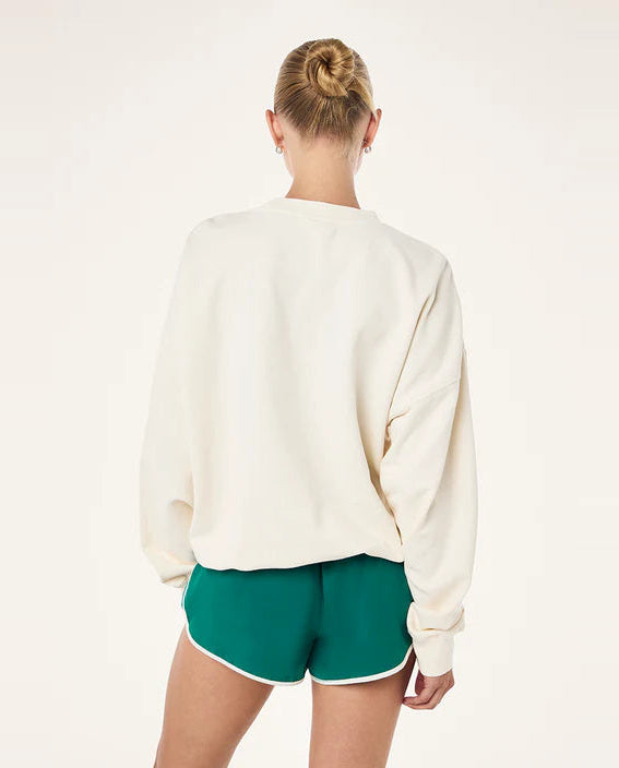 Person wearing a white sweatshirt and green shorts on a plain background