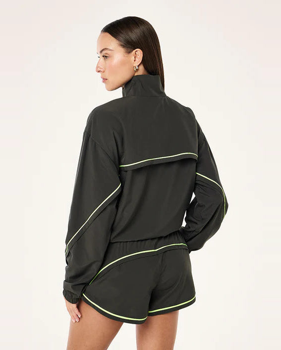 Woman wearing a grey tracksuit with lime green piping on a white background