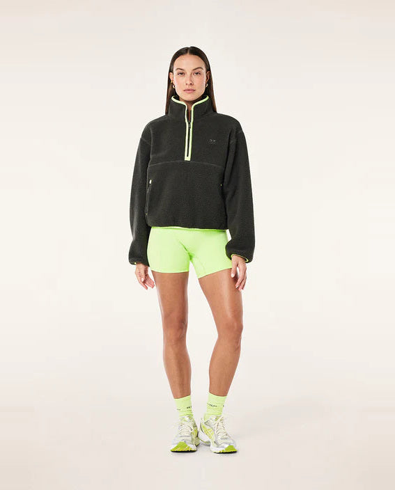 female model wearing  a grey teddy fleece with lime green highlights on a white background