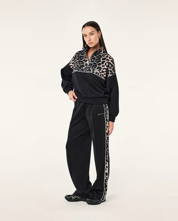 Person wearing a black tracksuit with leopard print accents on a white background