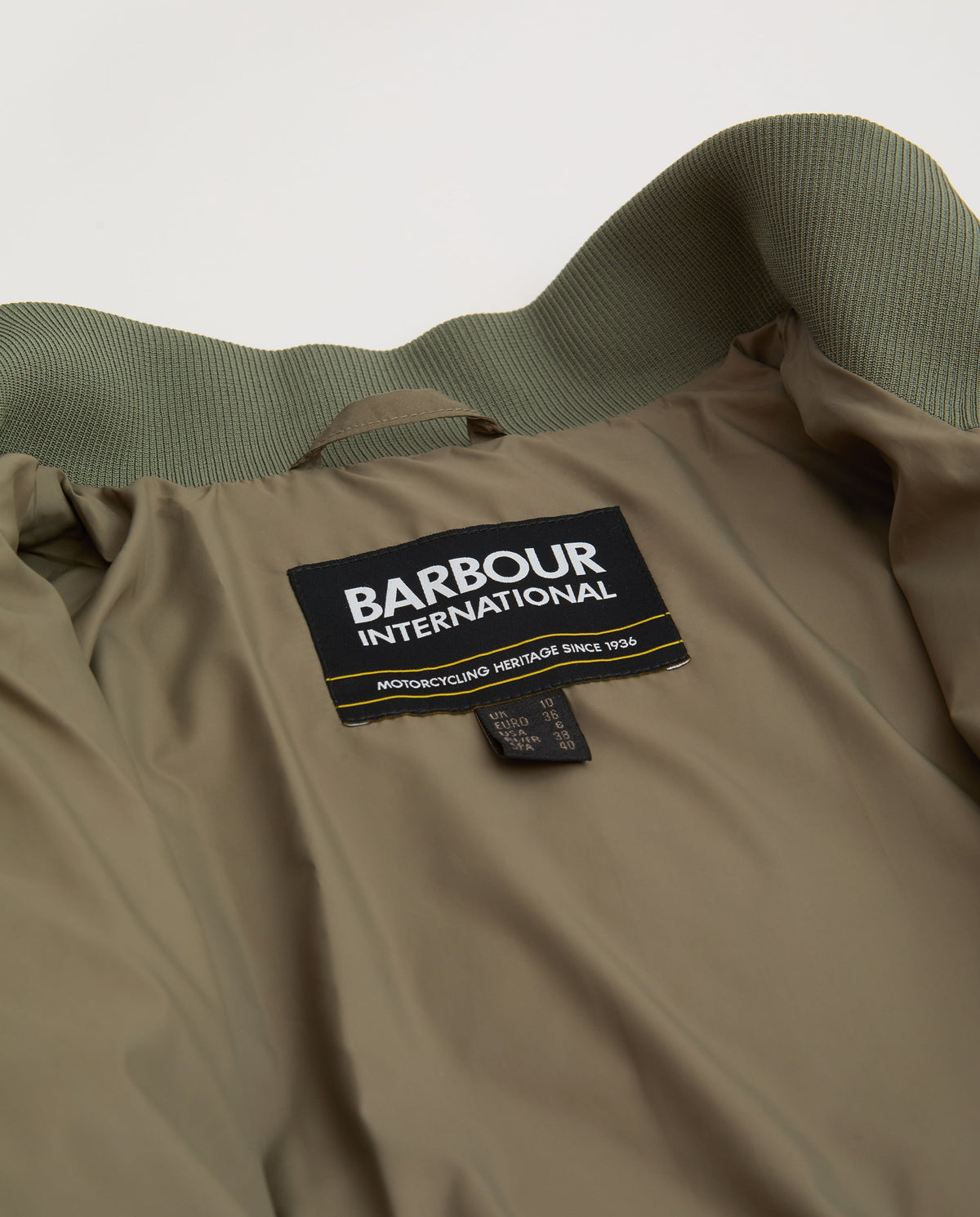 Barbour International label on a beige jacket with green collar.