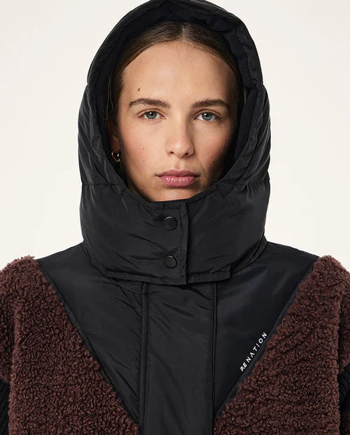 Person wearing a black hooded jacket with a brown garment underneath on a white background