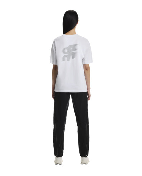 Person wearing a white t-shirt with a logo and black pants on a white background