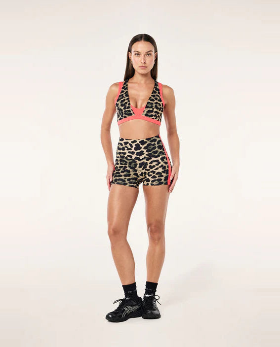 Woman wearing a leopard print sports bra and shorts set on a white background